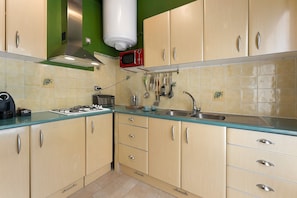 Una cucina con mobili beige, un fornello a gas, un forno a microonde e un lavello.