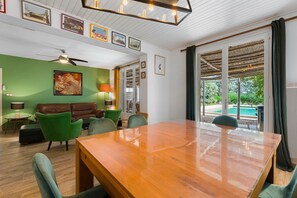 A spacious room with a wooden dining table, green chairs, a brown leather sofa, and a ceiling fan. - Country House 'Mas Saint Joseph' with Private Pool, Private Terrace and Wi-Fi (Meynes)