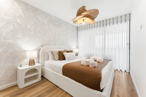 A modern bedroom with a large bed, a bedside table with a lamp, and a decorative ceiling light. - GuestReady-Luxurious Retreat with Rooftop Pool (Vila Nova de Gaia)