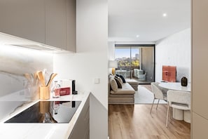 A modern kitchen with a built-in stove, a dining area with a round table and chairs, and a living space with a sofa and a view of the city. - GuestReady-Luxurious Retreat with Rooftop Pool (Vila Nova de Gaia)