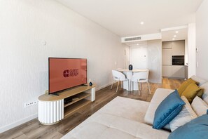 A modern living room with a flat-screen TV, a dining area, and a kitchen. - GuestReady-Luxurious Retreat with Rooftop Pool (Vila Nova de Gaia)