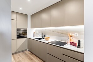 A modern kitchen with a marble countertop, built-in oven, and a sleek faucet. - GuestReady-Luxurious Retreat with Rooftop Pool (Vila Nova de Gaia)