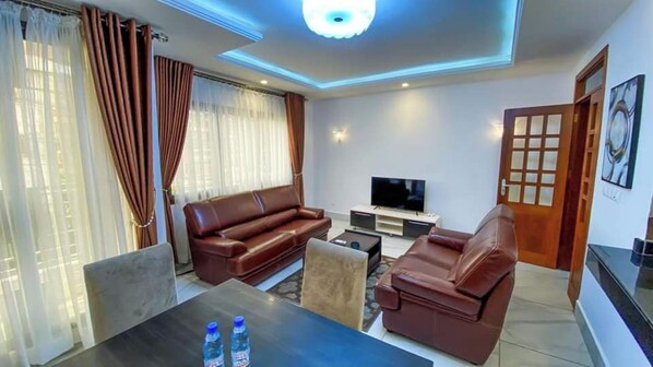 A living room with a sofa, a coffee table, a TV, and a door.
