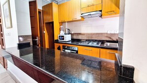 Una cocina con armarios de madera, encimera negra, estufa y microondas.
