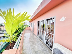 A balcony with a tiled floor, a metal railing, and a view of the cityscape.