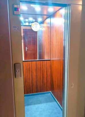 An elevator with a digital display, a wooden panel, and a door with a handle.