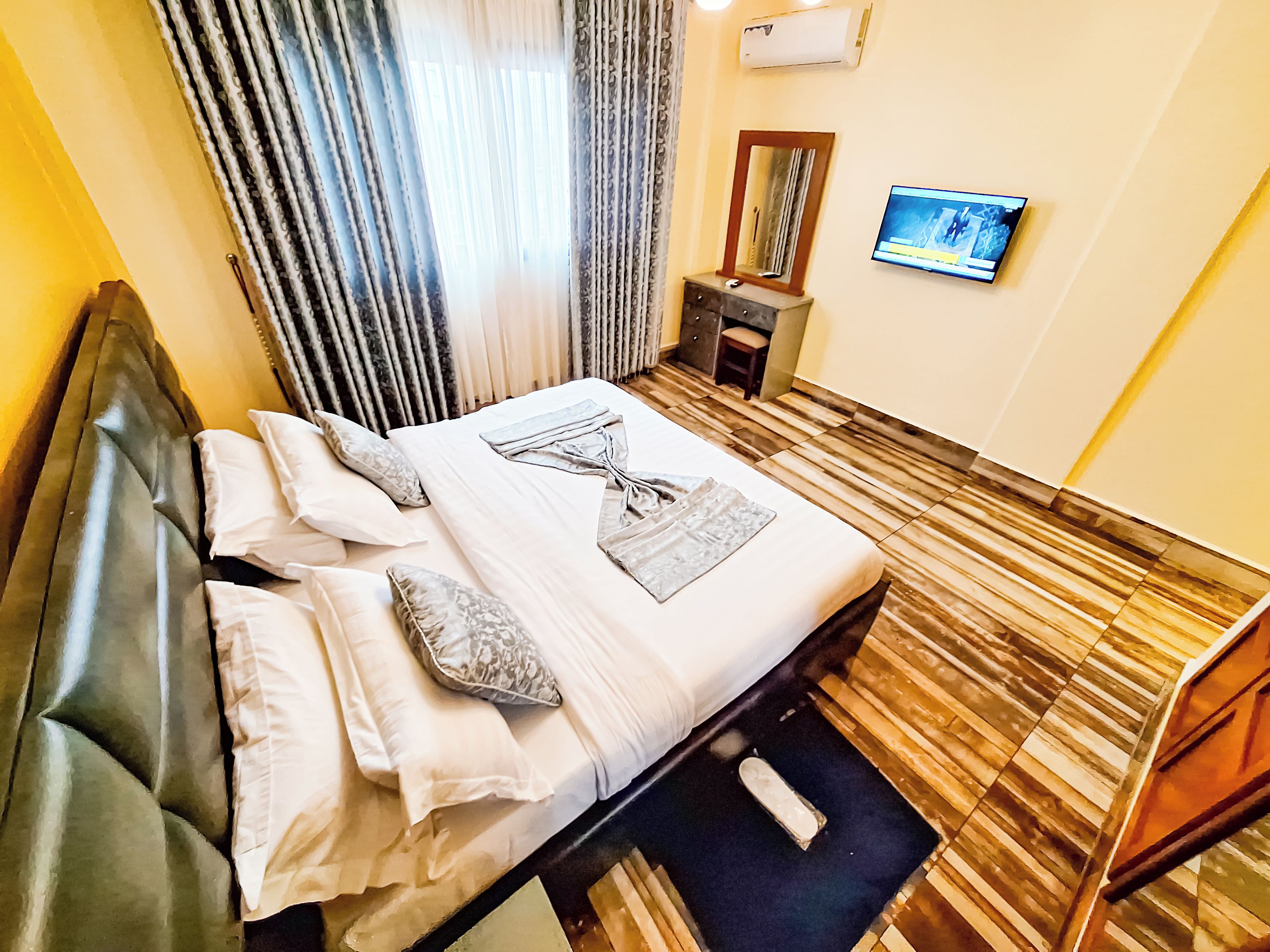 A hotel room with a bed, a small table, a chair, a television, and a mirror.