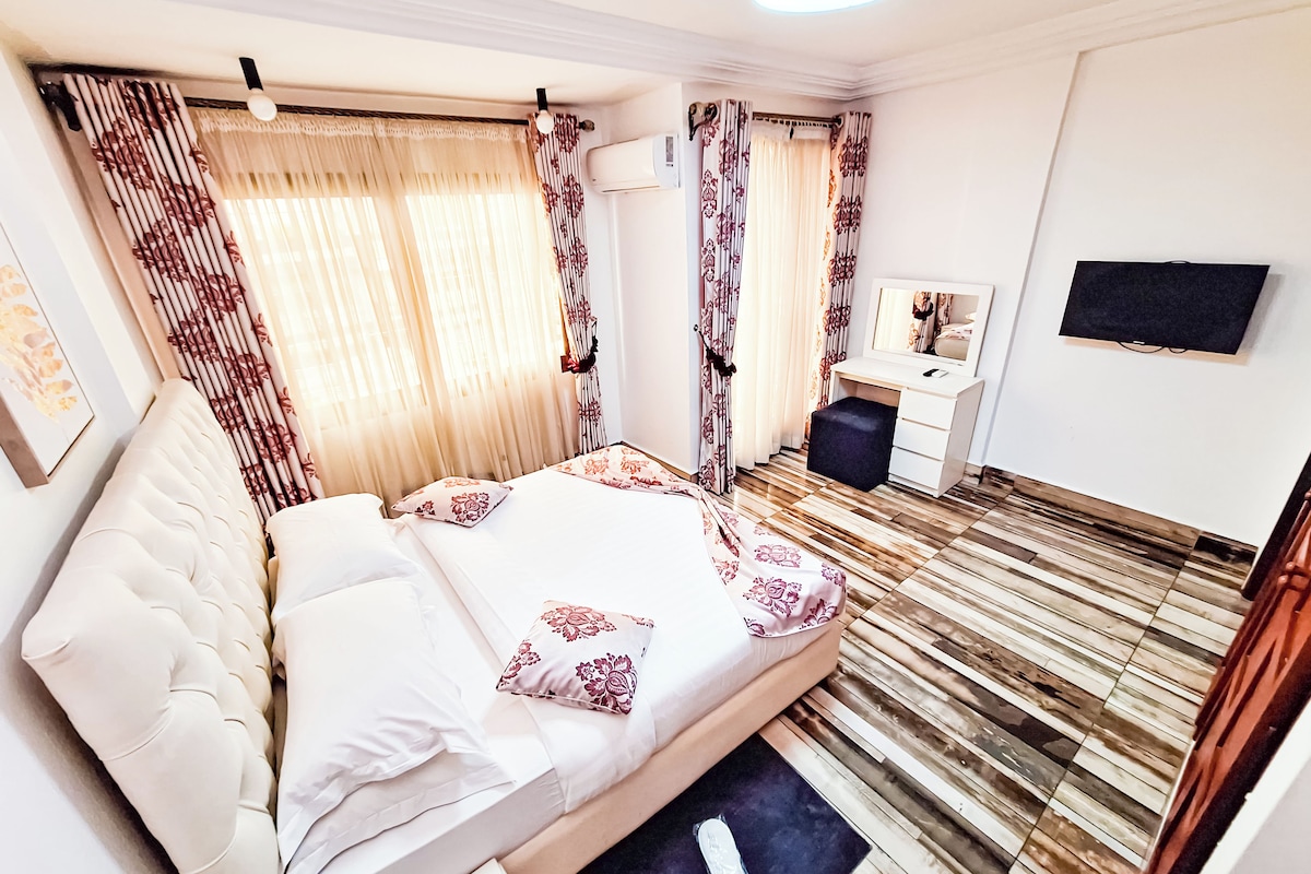 Een hotelkamer met een bed, een bureau, een stoel, een televisie en een raam met gordijnen.