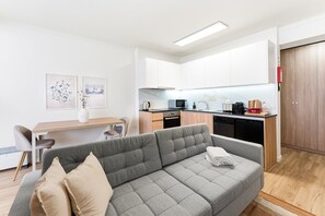A modern apartment with a grey sofa, a dining area, a kitchen with white cabinets, and a wooden wardrobe. - GuestReady - Charming Studio in Porto's Heart (Porto)