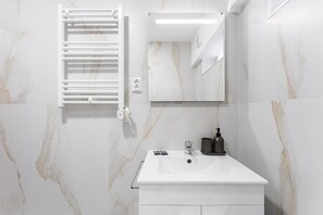 A bathroom with a white sink, a mirror, and a towel rack. - GuestReady - Charming Studio in Porto's Heart (Porto)