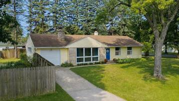 A single-story house with a front yard, a wooden fence, and a driveway leading to the garage.