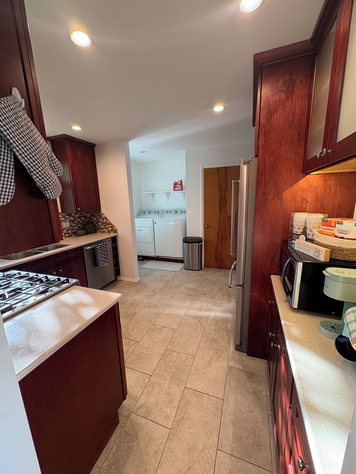 A kitchen with a gas stove, a refrigerator, and a microwave.