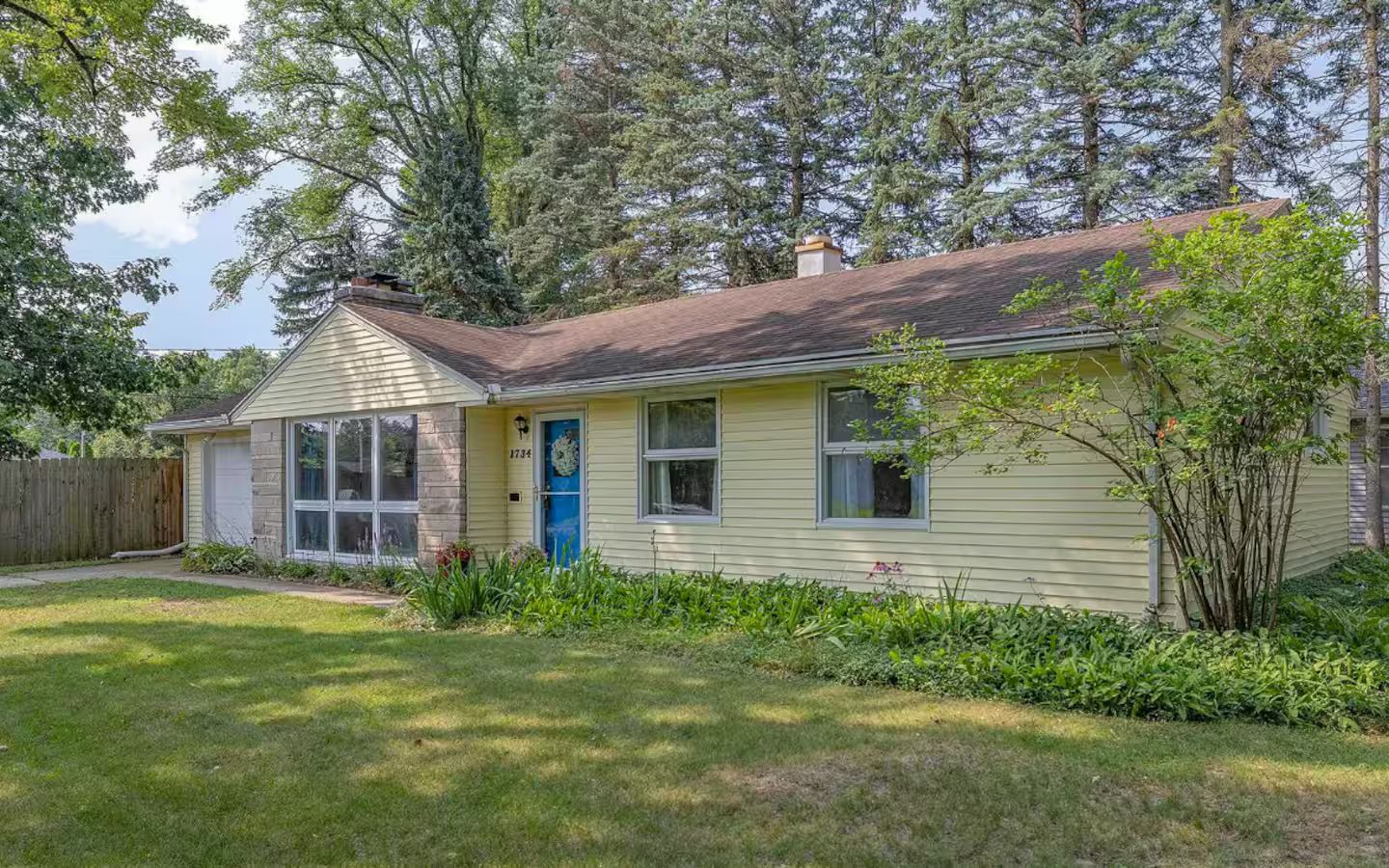 A single-story house with a front porch, a visible garage door, and a well-maintained lawn.