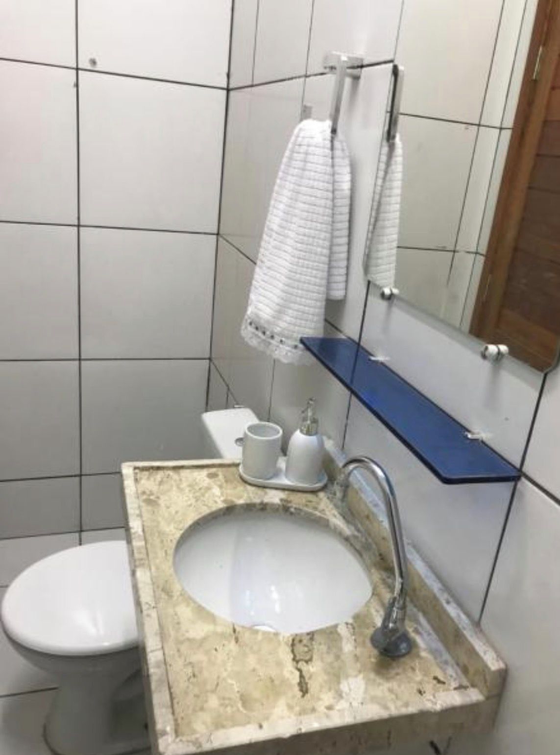 A bathroom with a white toilet, a sink with a marble countertop, and a mirror above the sink.