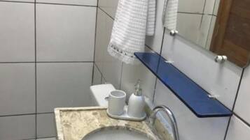 A bathroom with a white toilet, a sink with a marble countertop, and a mirror above the sink.