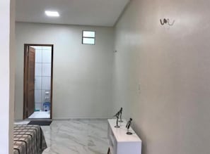 Una habitación de hotel con cama, una mesita con figuritas, un espejo y una puerta que da a otra habitación.
