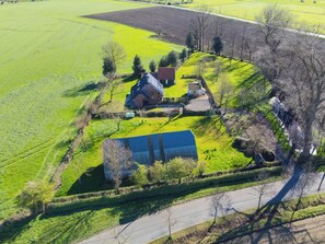 An aerial view of a rural property with a large barn, a house, and surrounding fields.