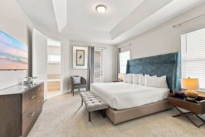 Ein modernes Schlafzimmer mit einem großen Bett, Nachttischen, einer Bank, einem Sessel und einem Gemälde an der Wand.