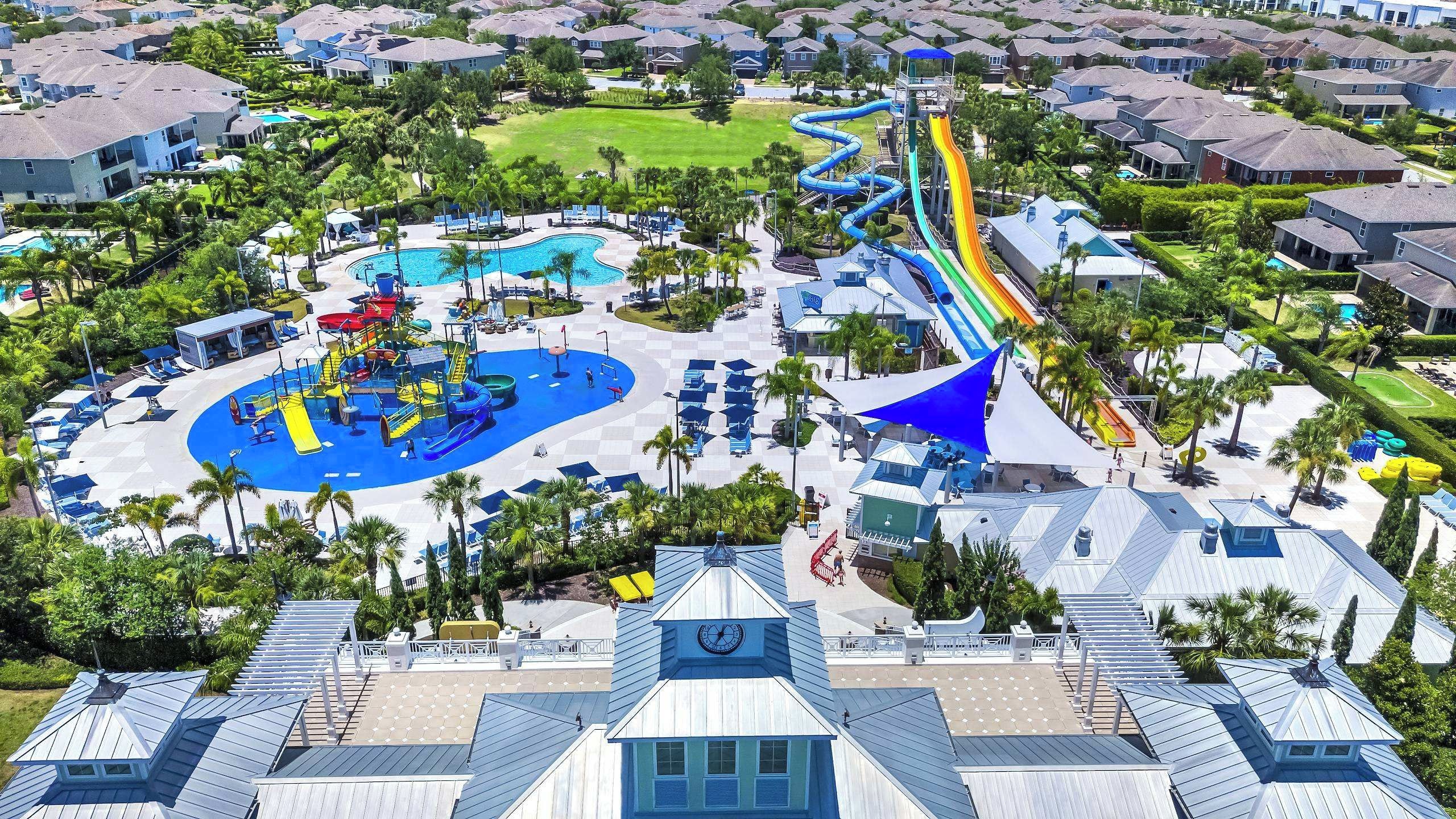 A resort with a large pool area, water slides, and a clock tower.