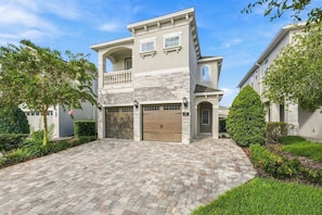 A two-story house with a garage, a balcony, and a well-maintained driveway. - Luxury Home Near Disney w/ Game & Themed Rooms, Waterpark Access - 397SF (Kissimmee)