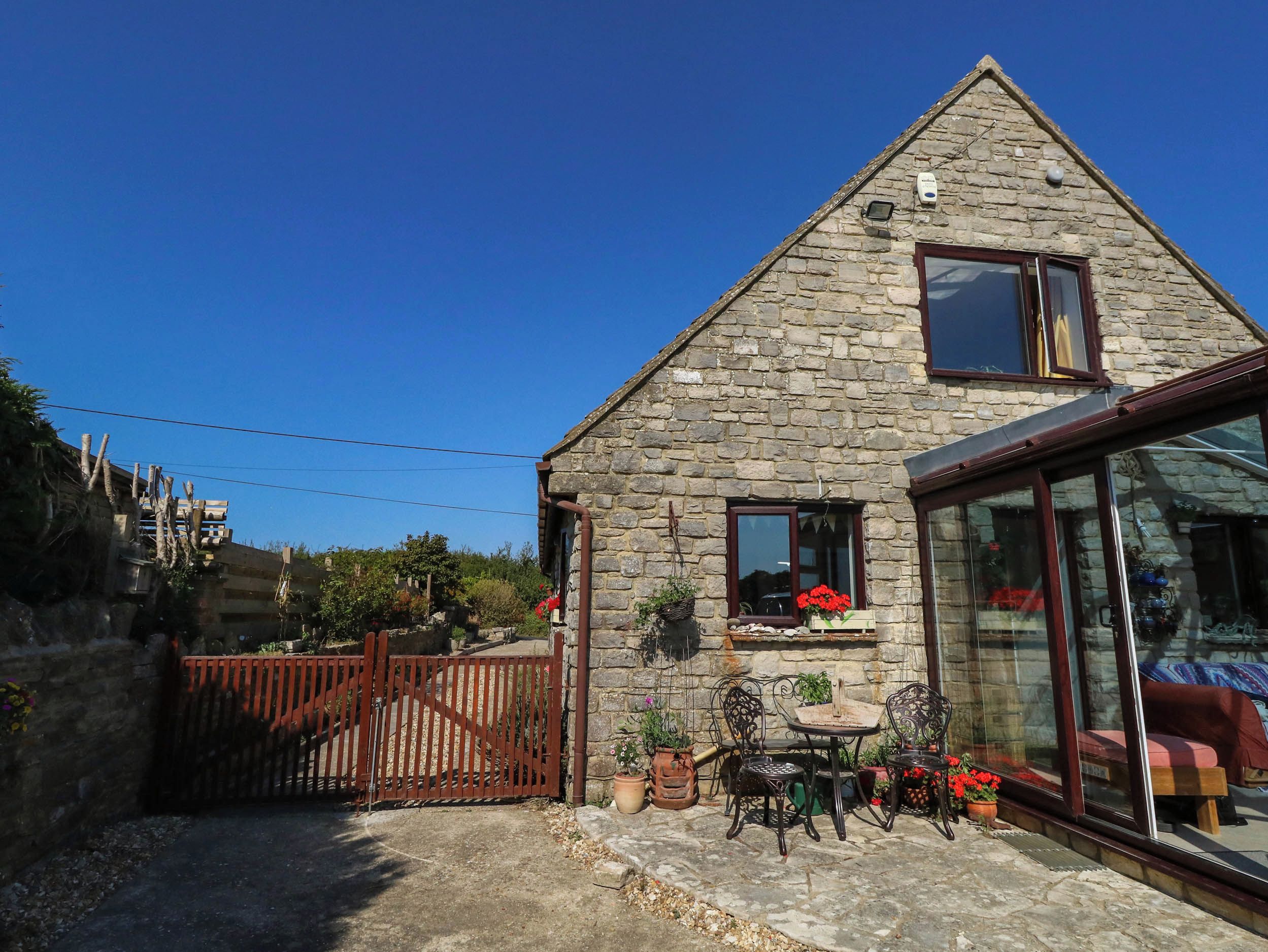 A stone house with a glass door, a wooden gate, and outdoor furniture.
