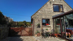 A stone house with a glass door, a wooden gate, and outdoor furniture. - Dunvant (Swanage)