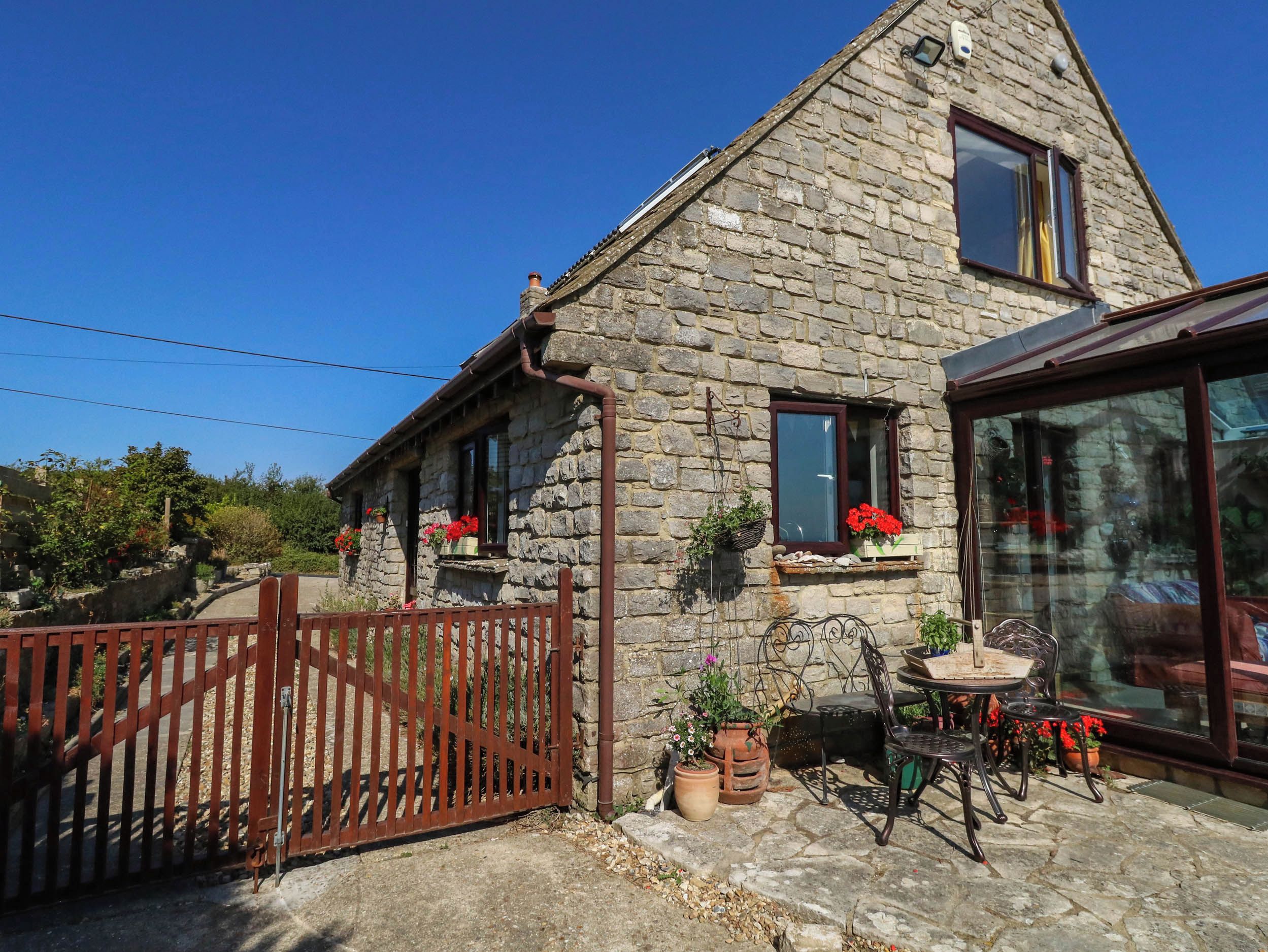 A stone house with a wooden gate, potted plants, and outdoor furniture.