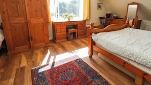 A bedroom with a wooden bed, a desk, a wardrobe, and a window with curtains. - Dunvant (Swanage)
