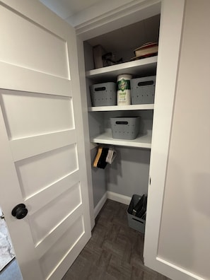 A white closet with shelves, a hanging rod, and a shoe rack.