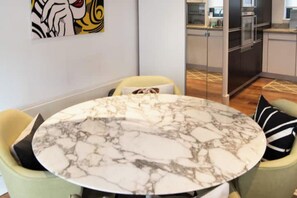A dining area with a marble table, two chairs, and a kitchen in the background. - Modern 2 BDR Balcony near Oxford Street (London)