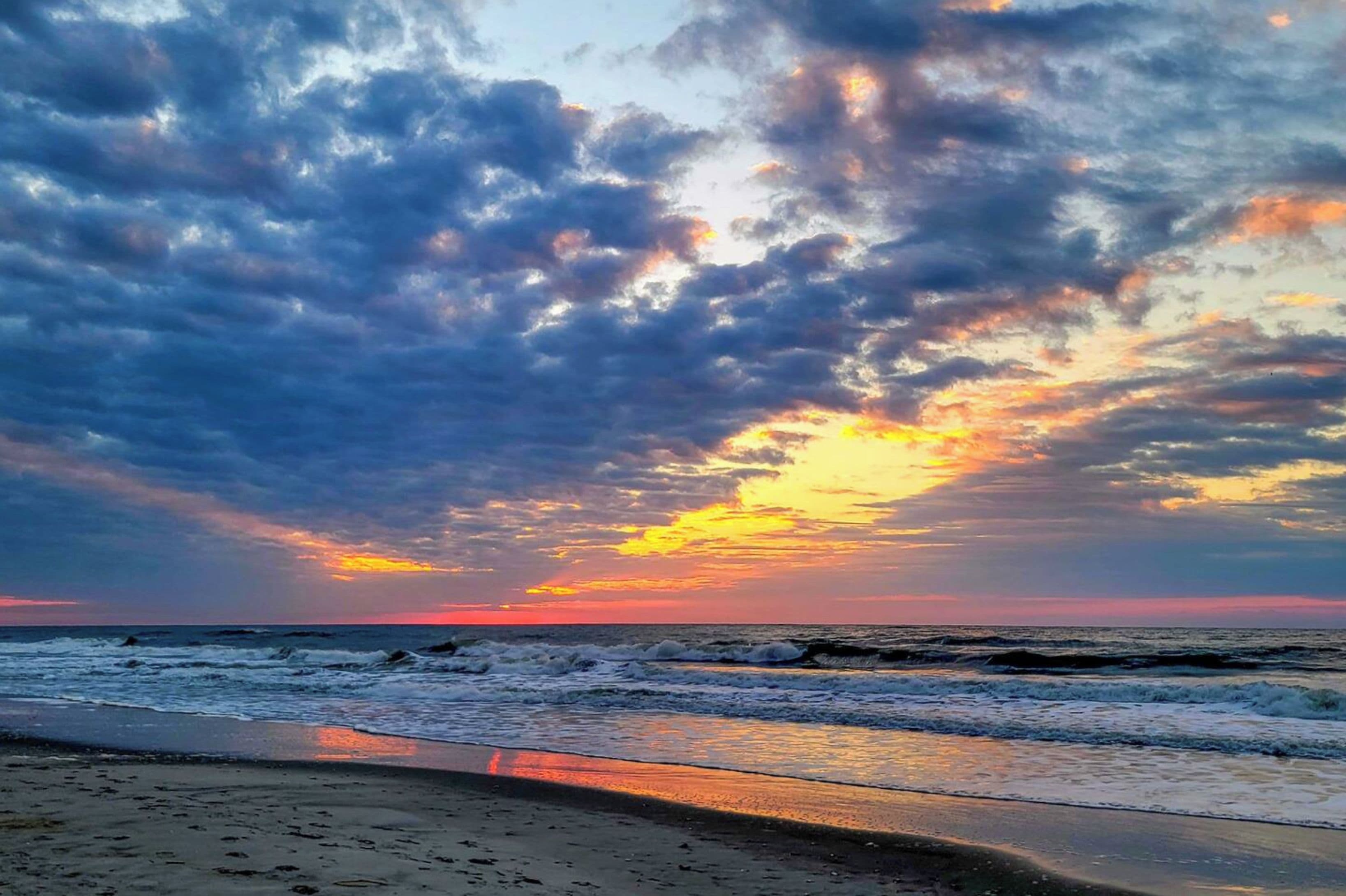 Uma praia com ondas e um pôr do sol.