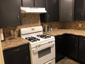Cozinha com fogão branco, armários pretos e painel de azulejos.