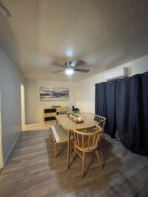 Ein Essbereich mit einem Holztisch, Stühlen, einem Deckenventilator und einem Bild an der Wand.