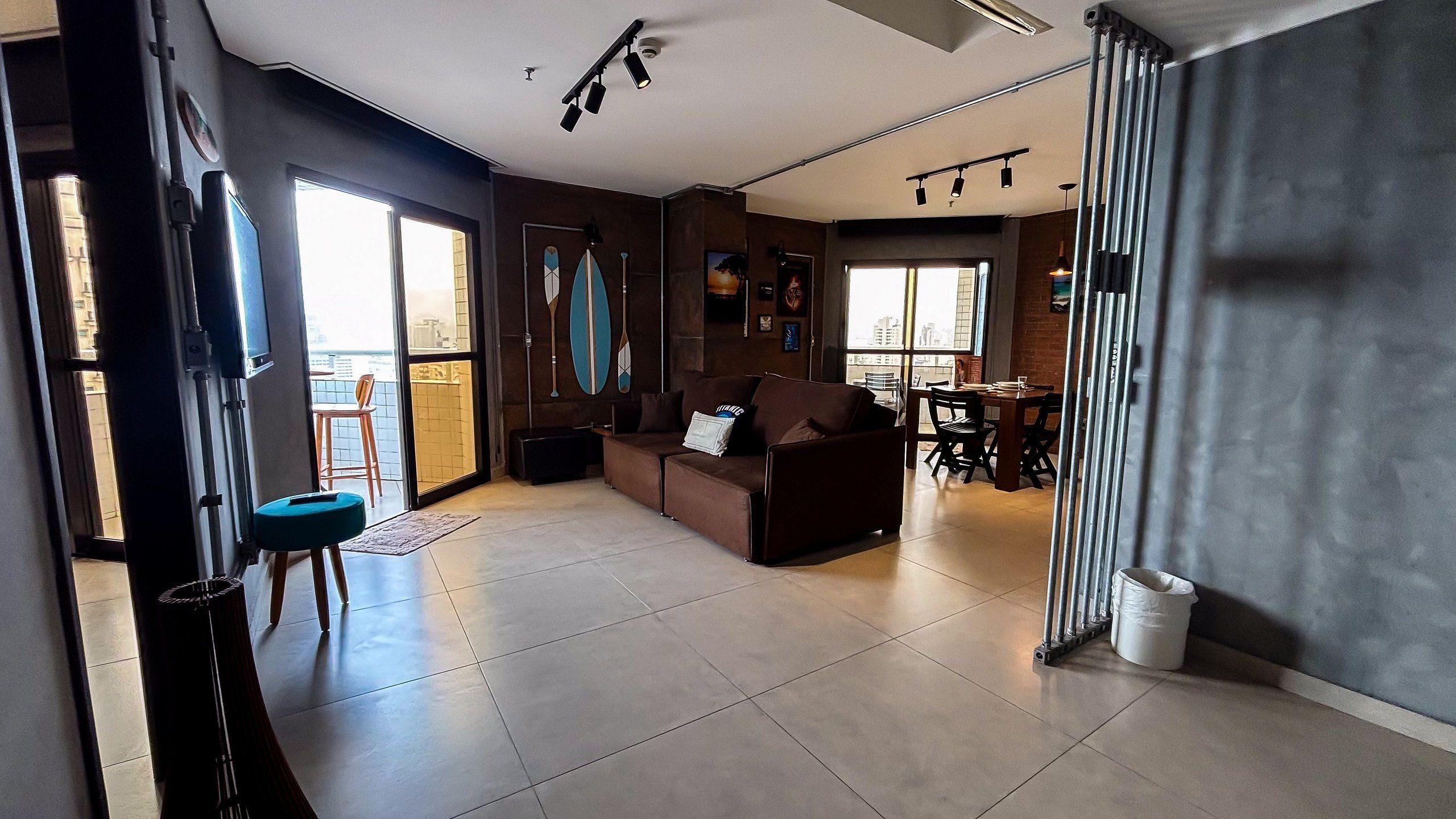 A spacious living area with a sofa, a dining table, and a view of the city through large windows.
