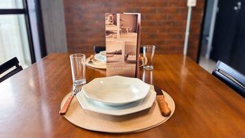 A dining table set with plates, cutlery, and glasses, with a brochure titled 'SUPER HOST BRASIL' in the background.