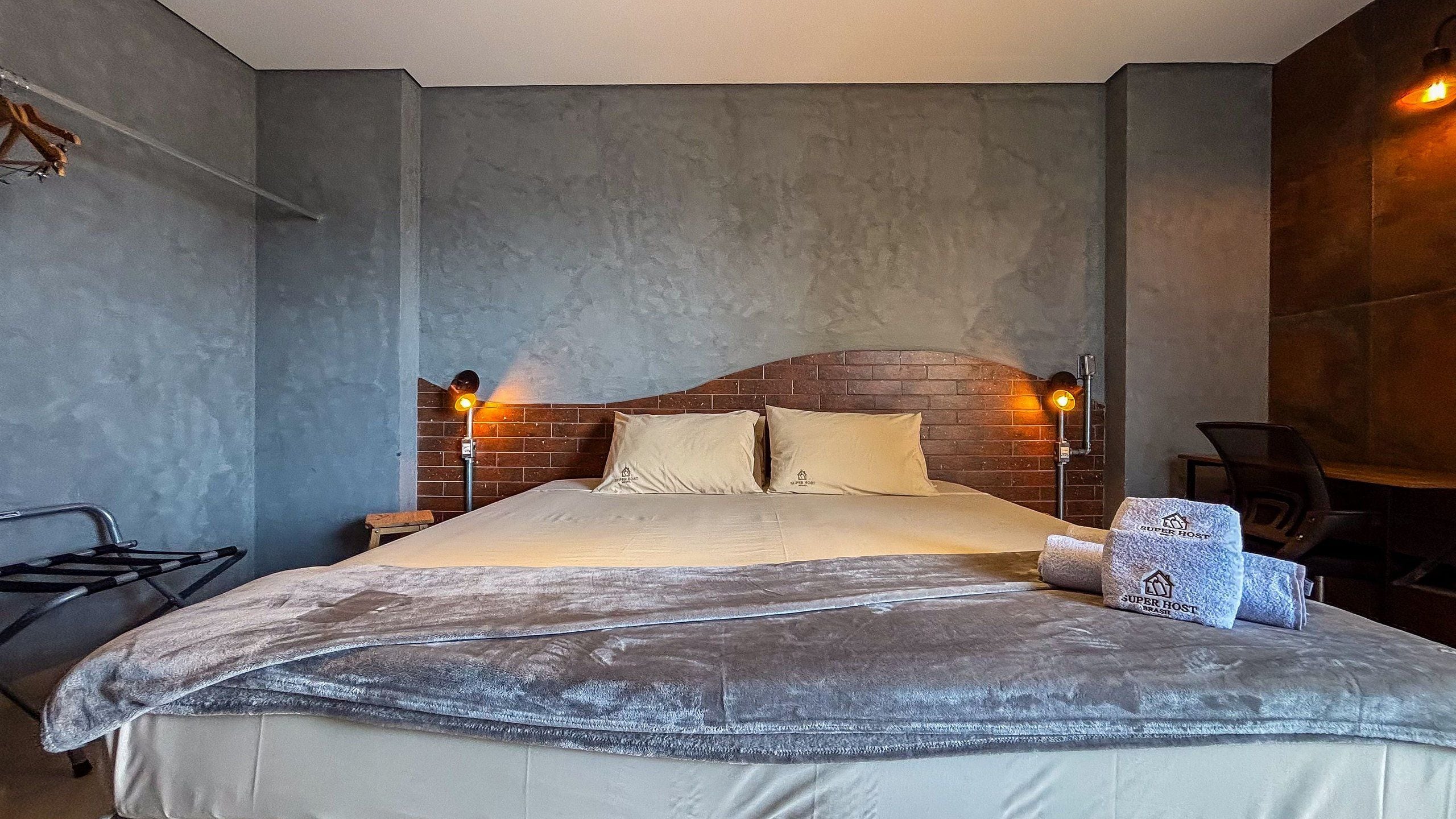 A bedroom with a bed, two bedside lamps, a chair, and a small table.