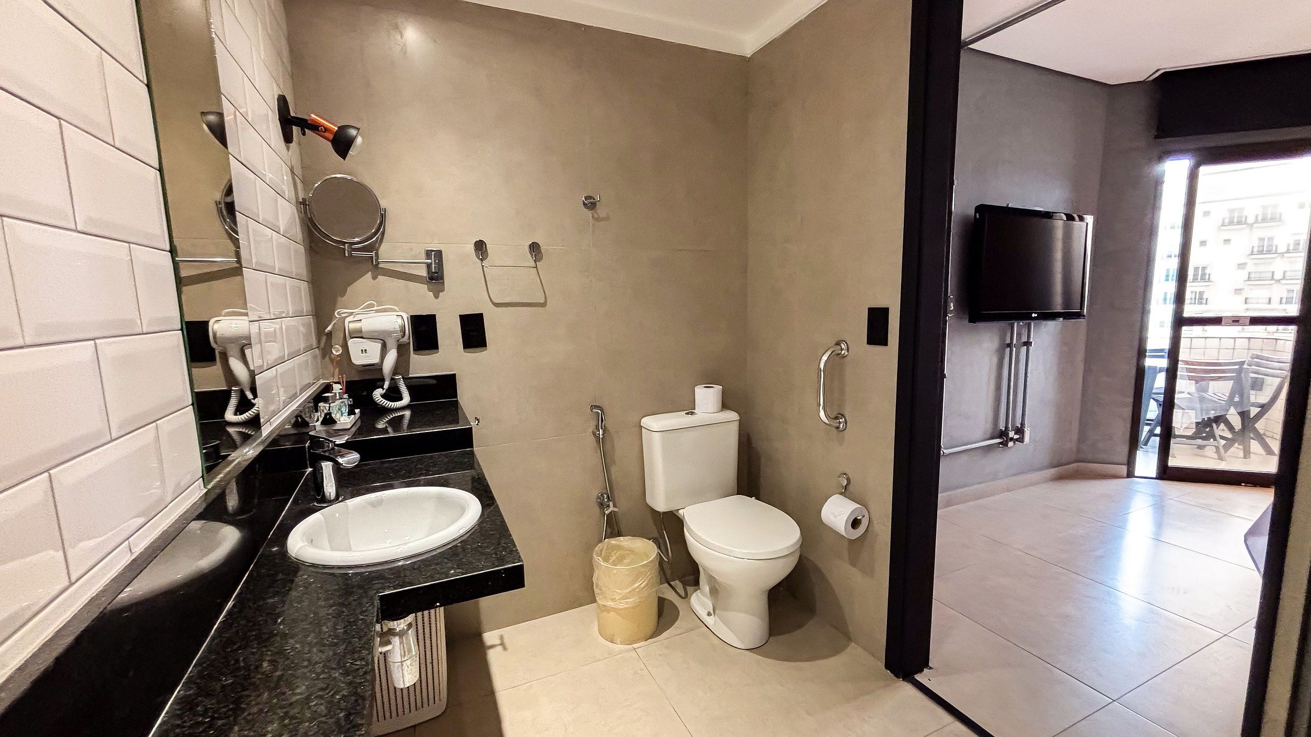 Un baño moderno con lavamanos de superficie negra, inodoro y espejo.