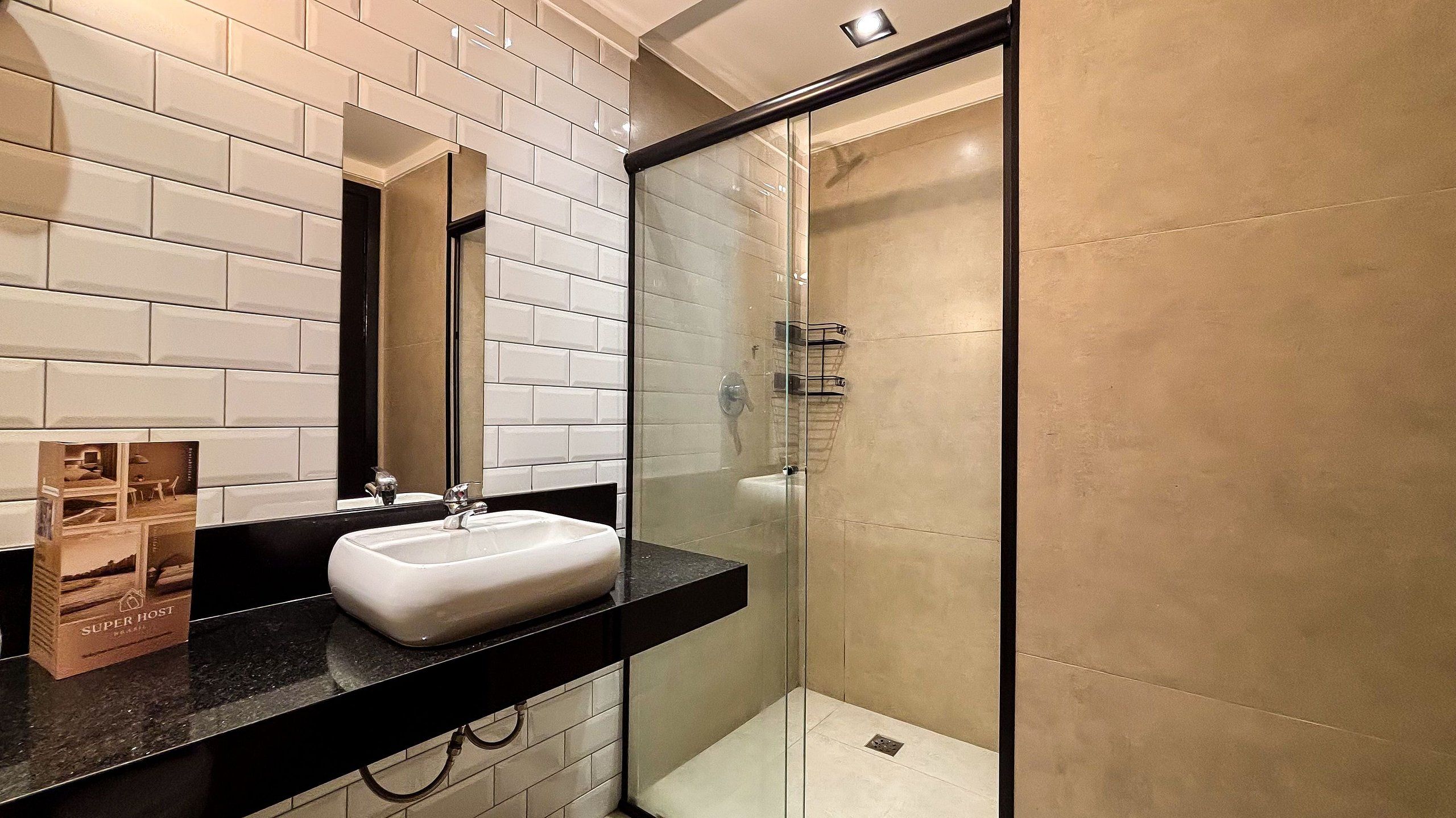 A modern bathroom with a white sink, black countertop, and a glass shower enclosure.