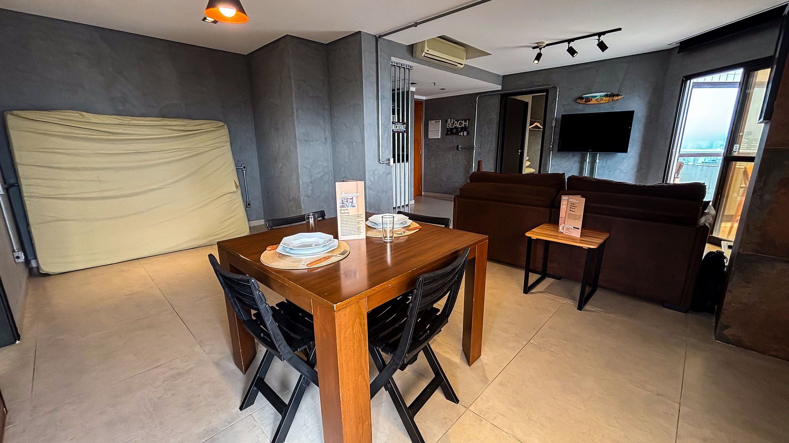 Una sala de estar moderna con comedor, sofá y televisor montado en la pared.