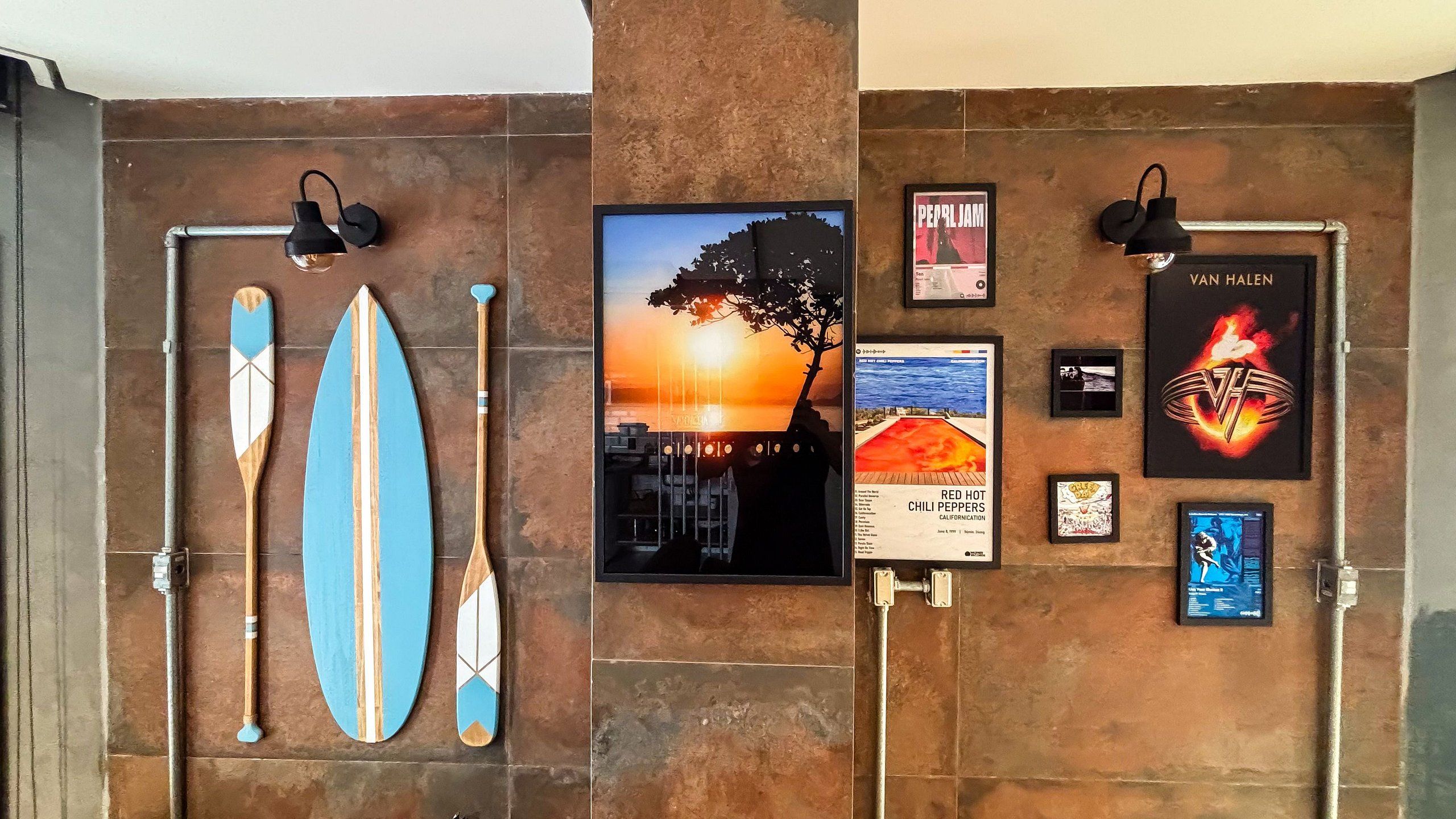 Una pared con tablas de surf, un cartel de atardecer y un cartel de una banda.