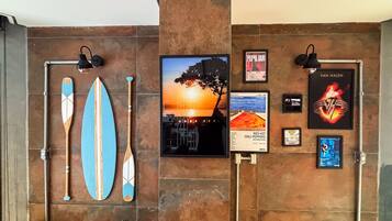 Una pared con tablas de surf, un cartel de atardecer y un cartel de una banda.