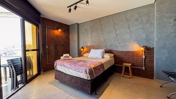 Un dormitorio moderno con una cama, un taburete y una silla.