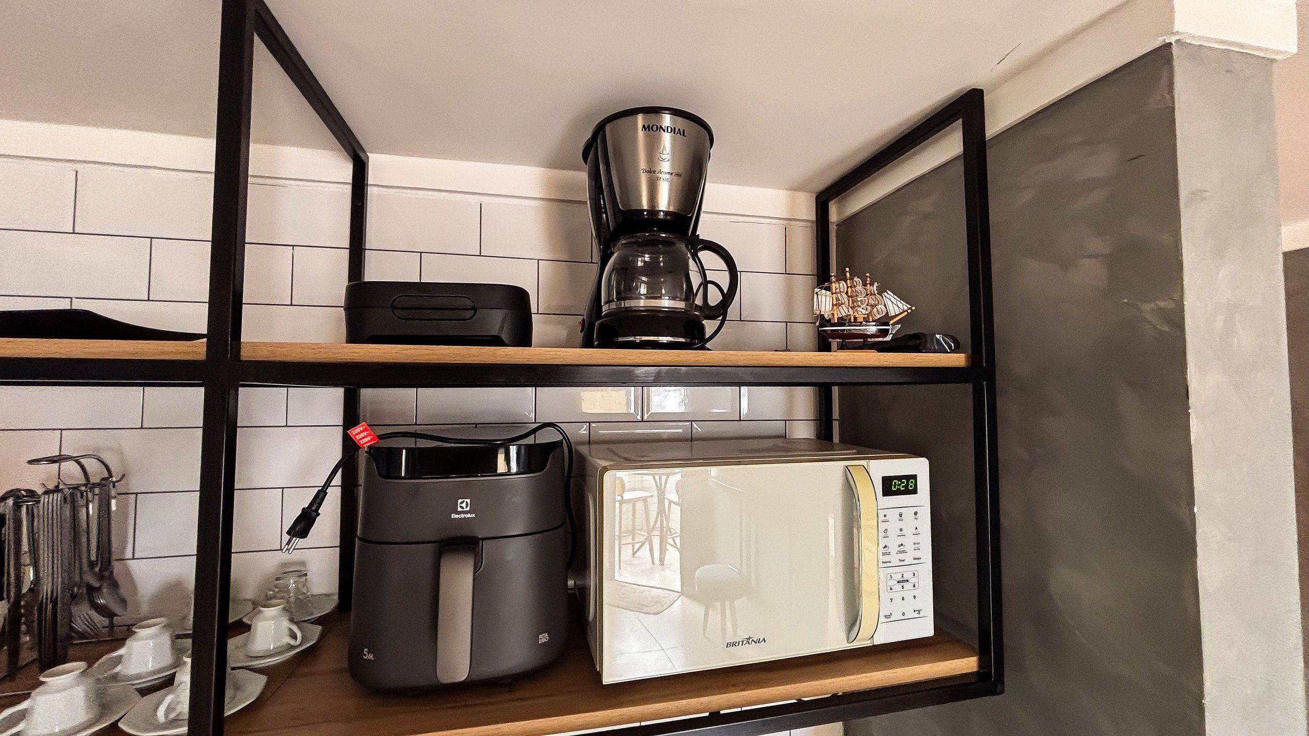 A kitchen with a coffee maker, a toaster, and a microwave on a wooden shelf.