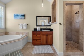 Un bagno con una vasca, un lavabo con specchio, una doccia e un quadro appeso al muro.