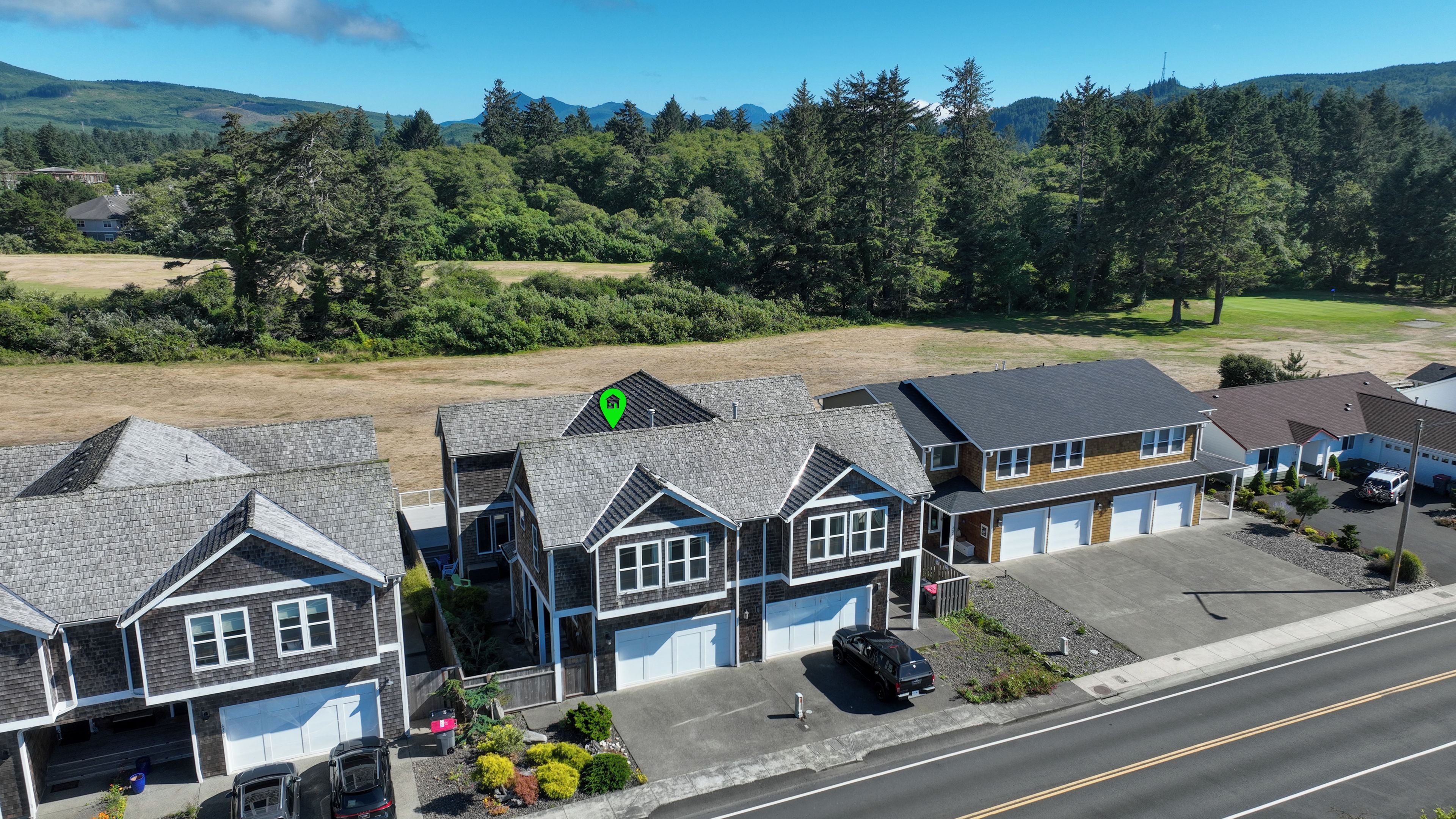 Un quartier résidentiel avec des maisons, une route et un paysage vallonné en arrière-plan.