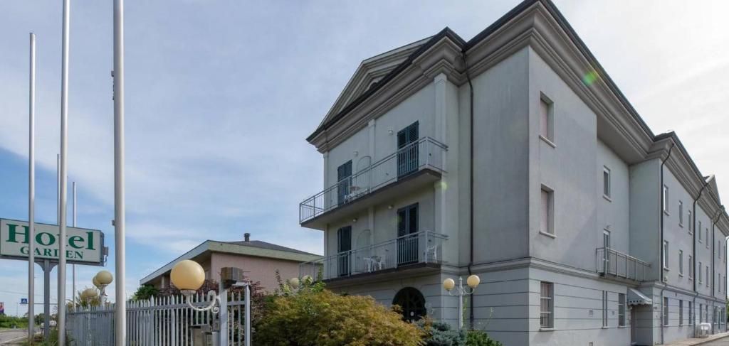 A multi-story hotel with balconies, a garden sign, and a well-maintained exterior.