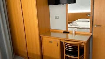 Une chambre d’hôtel avec un bureau en bois, une chaise, un téléviseur fixé au mur et une armoire.