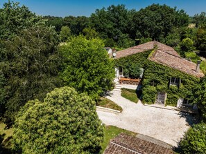 A house with a stone pathway leading to a wooden deck, surrounded by dense greenery. - La Guate - Maison avec piscine - Saint-Émilion (Daubèze)