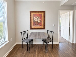 A dining area with a table and chairs, a framed picture on the wall, and a door leading to another room. - Sleepover | Tranquil 1BD/1BA+ Gym - Corpus Christi (Corpus Christi)