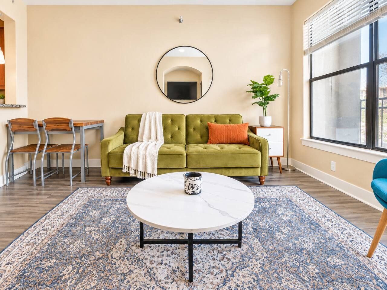 A living room with a green sofa, a round coffee table, and a patterned rug.